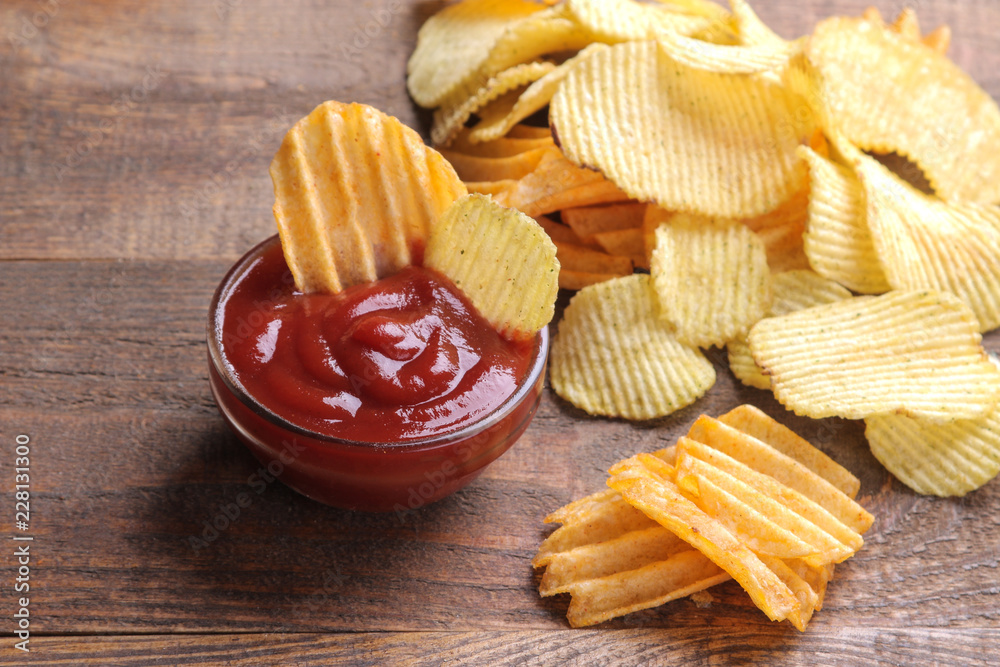 Many different chips with red sauce on a brown wooden table. Snacks. Many different chips with red sauce on a brown wooden table. Snacks.