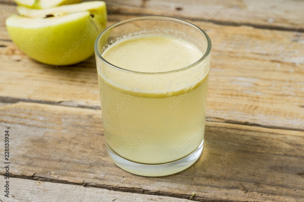 Homemade fresh squeezed apple juice in a clear glass with apple on a side Homemade fresh squeezed apple juice in a clear glass with apple on a side