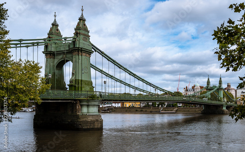The Hammersmith Bridge, a suspension bridge that crosses the River Thames in west London. Hammersmith is in the background, photo taken from Barnes.