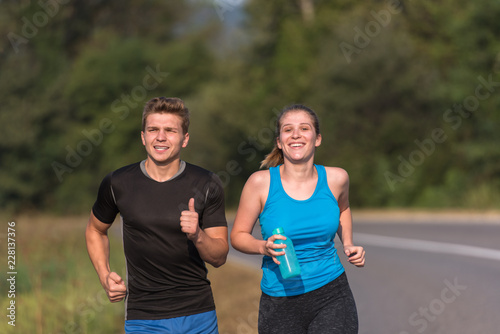 Fototapeta Naklejka Na Ścianę i Meble -  young couple jogging along a country road