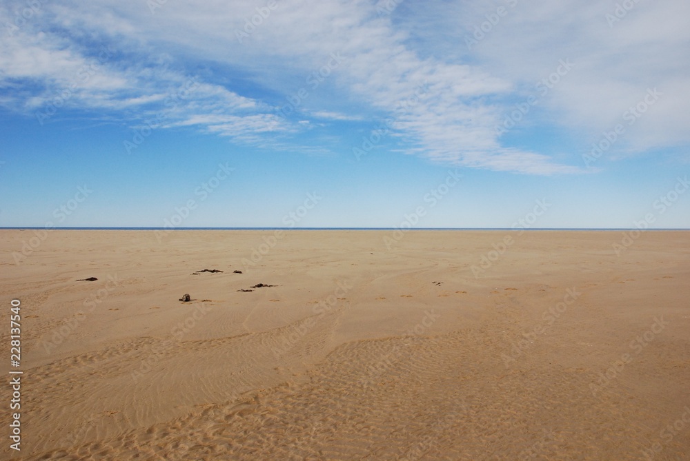 Scenery of clear brown sand of the beach and beautiful white blue sky with horizontal line at day time
