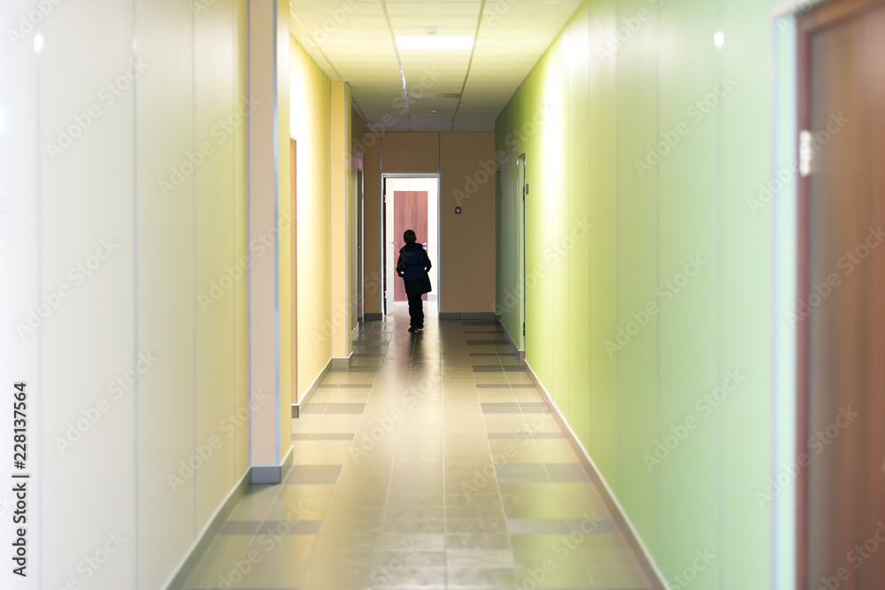 Corridor in school silhouette of a man. A school age child is walking down the hall.