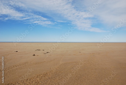 Scenery of clear brown sand of the beach and beautiful white blue sky with horizontal line at day time