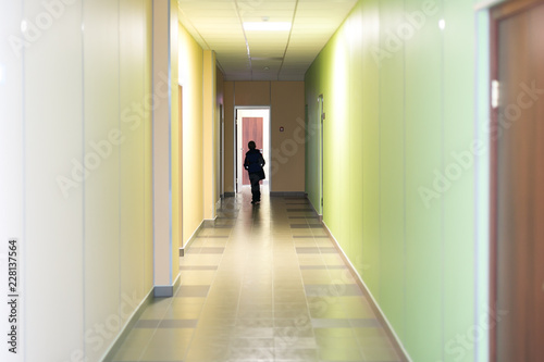 Corridor in school silhouette of a man. A school age child is walking down the hall.