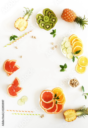 Summer tropical fruits composition table  top view background. . Pineapples, kiwi, lime, grapefruit, orange,  pistachios on white background. Summer food concept. Flat lay,  copy space