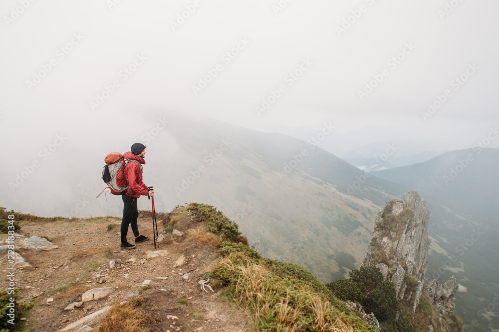 man with hiking equipment standing on rock's edge