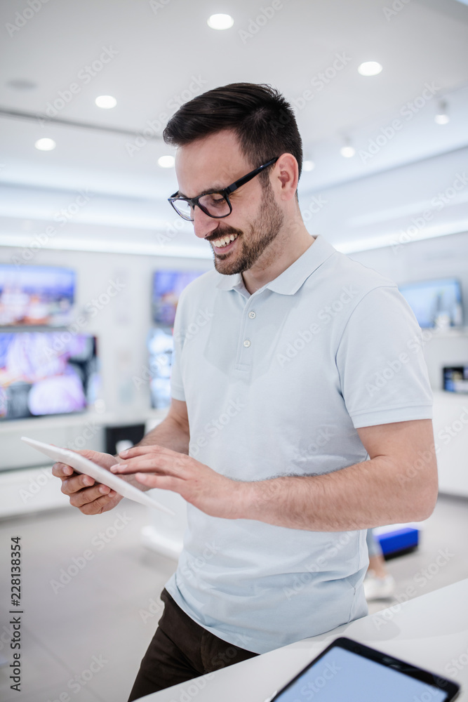 Man standing in tech store and trying out tablet. Man standing in tech store and trying out tablet.