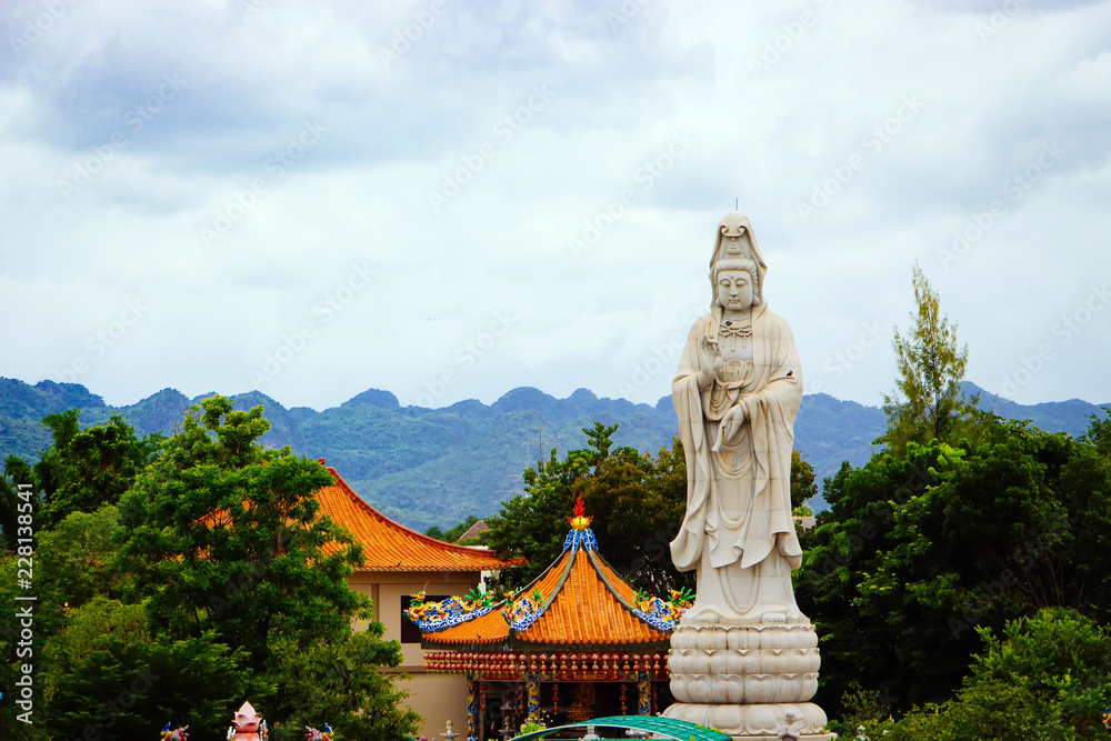 Bodhisattva Guan Yin statue along the River Kwai in front of the mountain in Kanchanaburi, Thailand. Bodhisattva Guan Yin statue along the River Kwai in front of the mountain in Kanchanaburi, Thailand.
