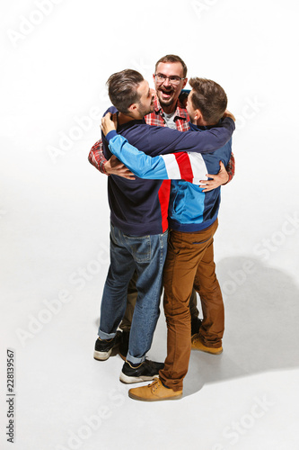 Three friends in casual colorful wear standing and laughing together. Best friends enjoying life. Two men having fun. Hugging day concepts