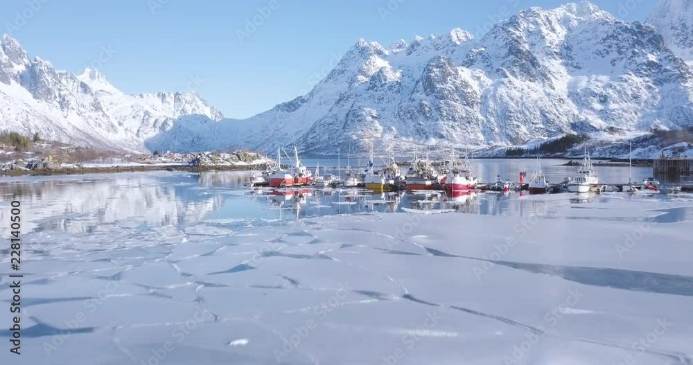 Aerial footage of Lofoten Islands winter scenery with traditional fishing boats lying in harbor on a sunny day, Norway, Scandinavia
