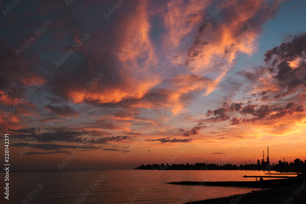 Naklejka premium beautiful red sunset with orange clouds above the coasline