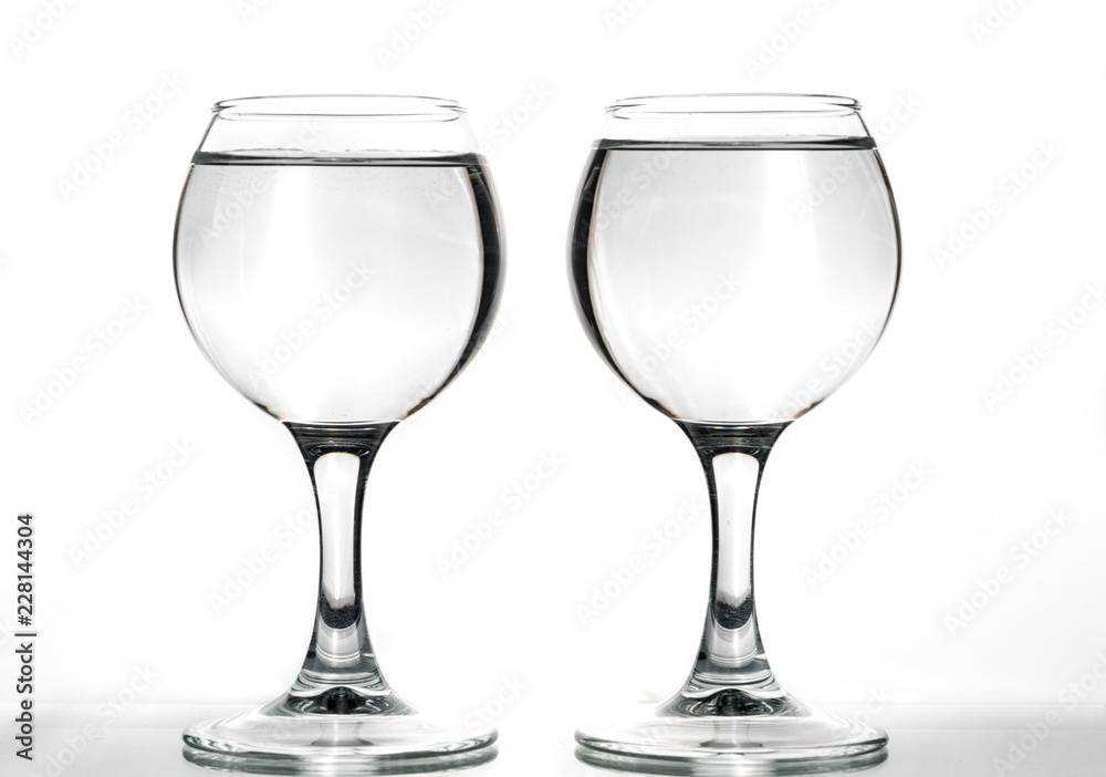 Two round glasses empty or full with waves of liquid on a white background