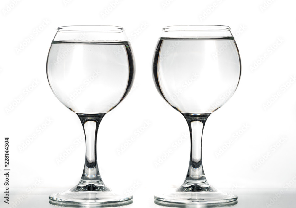 Two round glasses empty or full with waves of liquid on a white background Two round glasses empty or full with waves of liquid on a white background