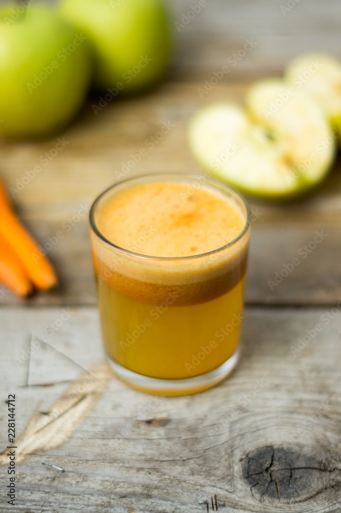 Homemade fresh squeezed apple and carrot healthy juice in a clear glass with apple and carrot on a side Homemade fresh squeezed apple and carrot healthy juice in a clear glass with apple and carrot on a side