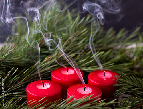 spruce green branch and red extinct advent candles from which smoke comes photo