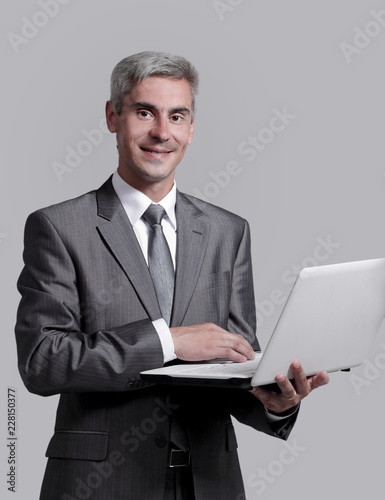 businessman standing with an open laptop