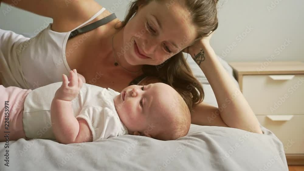 A Portrait of a beautiful mother with her 2 month old baby in the bedroom A Portrait of a beautiful mother with her 2 month old baby in the bedroom