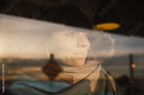 Woman in warm outwear looking away through window photo