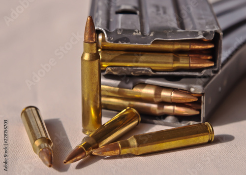 Two metal rifle magazines, one stacked upon the other, loaded with .223 caliber bullets with four additional bullets of the same caliber in front of them