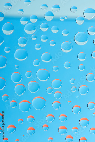 close-up view of transparent water drops on bright blue background