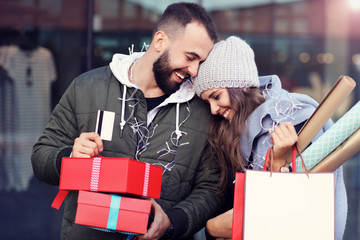 Portrait of happy couple with shopping bags after shopping in city