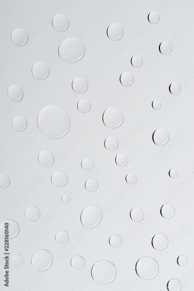 close-up view of transparent water drops on light grey background