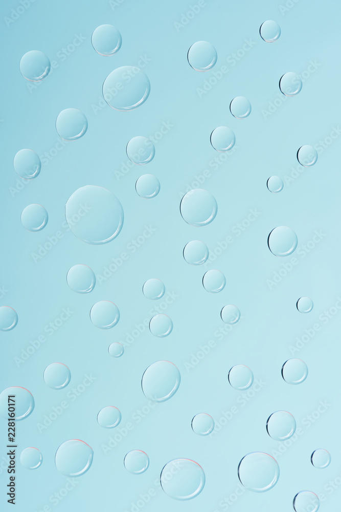 close-up view of transparent water drops on light blue background