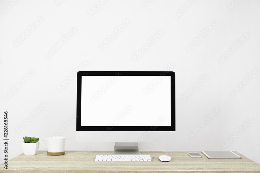 Modern PC Monitor and white screen, mouse, keyboard and some stuff on the wooden table. White background and copy space. Business or Work space theme Modern PC Monitor and white screen, mouse, keyboard and some stuff on the wooden table. White background and copy space. Business or Work space theme