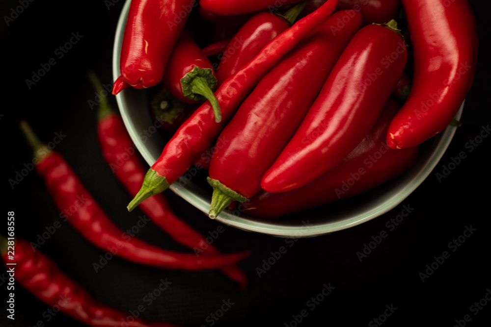 Red chili peppers in a plate on a dark background, top view