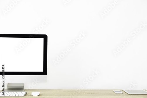 Modern PC Monitor and white screen, mouse, keyboard and some stuff on the wooden table. White background and copy space. Business or Work space theme photo