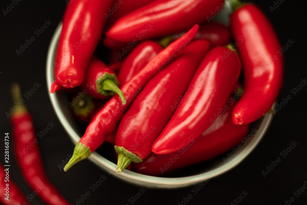 Red chili peppers in a plate on a dark background, top view
