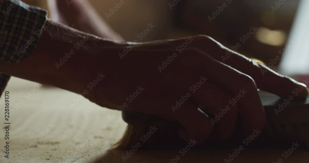 Close up of a carpenter while he is cleaning a wooden trunk after he finished to cut it. Close up of a carpenter while he is cleaning a wooden trunk after he finished to cut it.