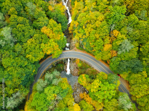 Aerial Drone Shot of waterfall flowing under Mountain Back road in Autumn / Fall foliage.   Blue Ridge in the Appalachian Mountains near Asheville, North Carolina. Sunburst Falls photo