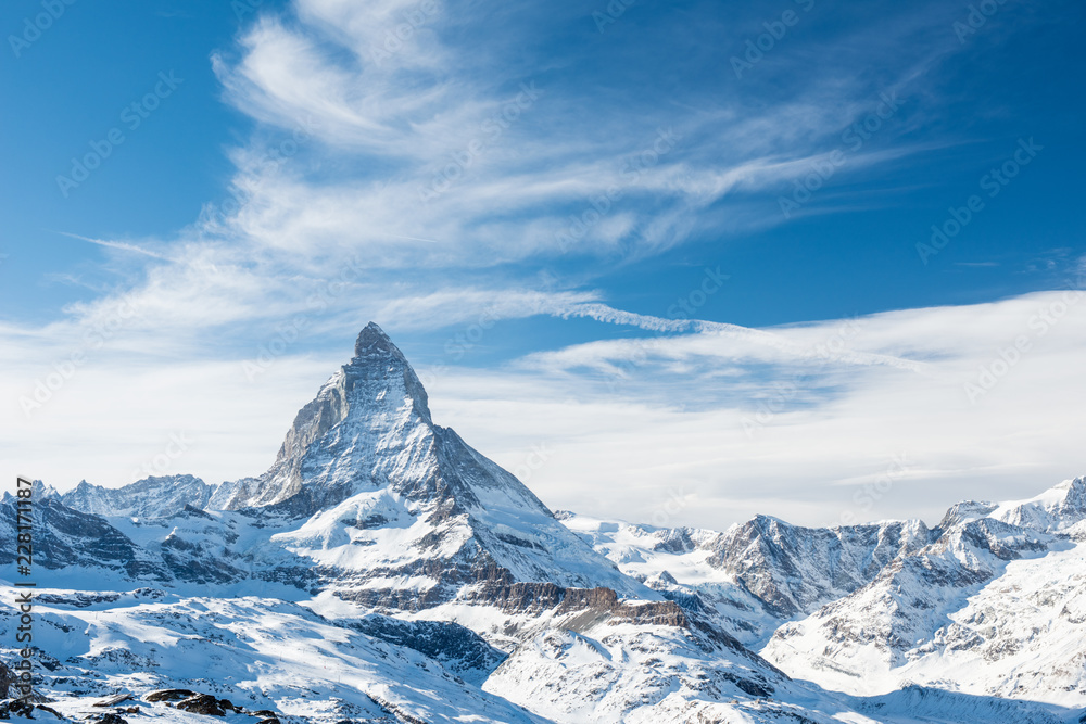 Obraz premium Sceniczny widok na śnieżnym Matterhorn szczycie w słonecznym dniu z niebieskim niebem i dramatycznymi chmurami w tle, Szwajcaria.