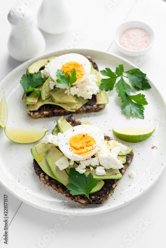 Rye bread toast with avocado, egg, white cheese on a plate. Healthy breakfast, healthy eating concept