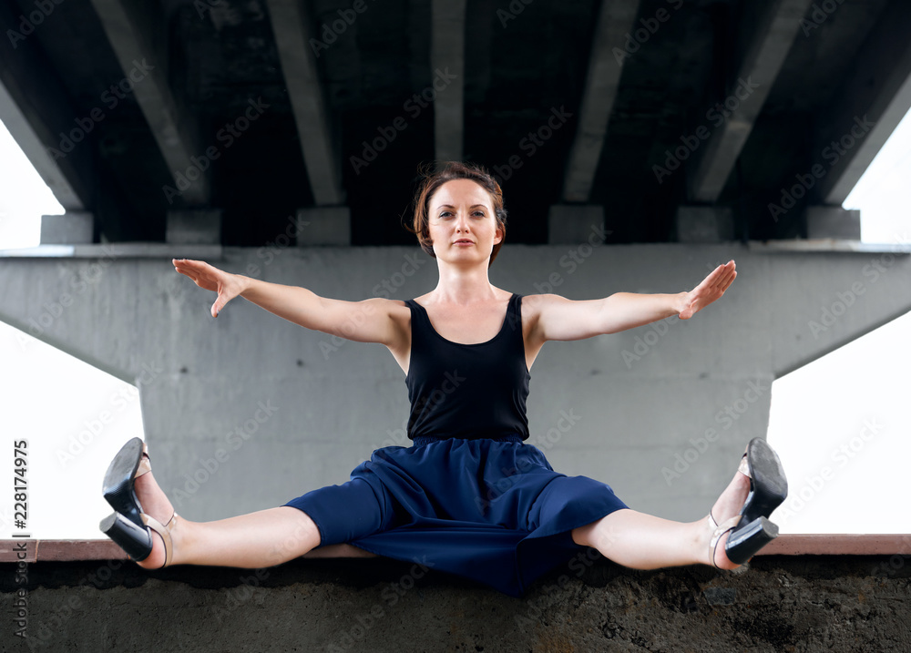 Fototapeta premium young girl posing under the bridge, dressed in black, modern architecture