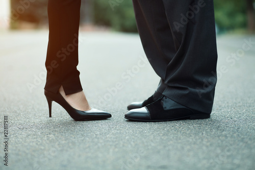 Closeup of businessman's and businesswoman's legs outside. Wearing luxury shoes.