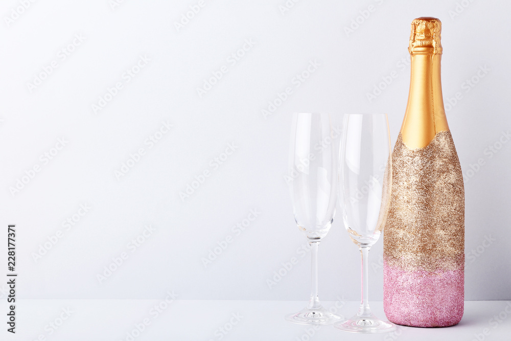 Decorated champagne bottle with glasses on grey background