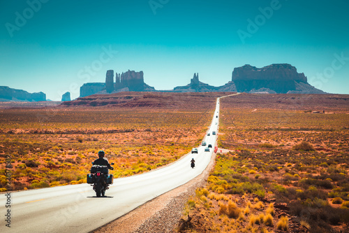 Canvas-taulu Biker on Monument Valley road at sunset, USA