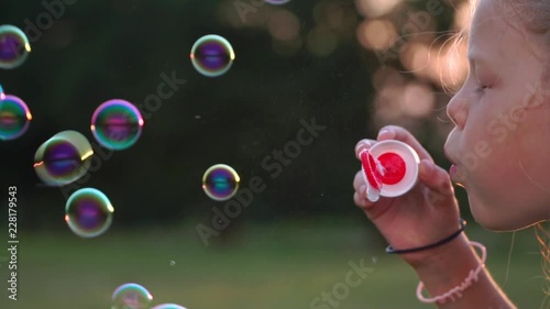 little blond girl blowing bubbles