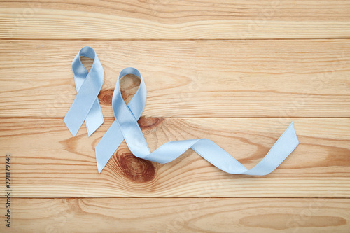 Blue ribbon on brown wooden table. Prostate cancer concept