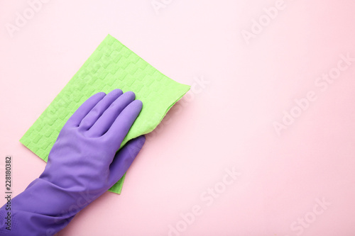 Hand in glove with sponge on pink background