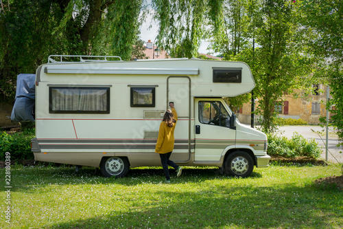 Jovem a entrar na sua motorhome parqueada em cima de relva.