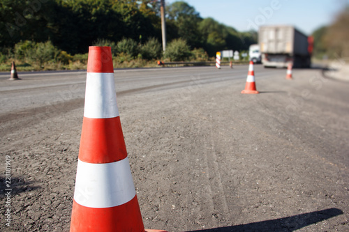 traffic cone, with white and orange stripes on gray asphalt, copy space