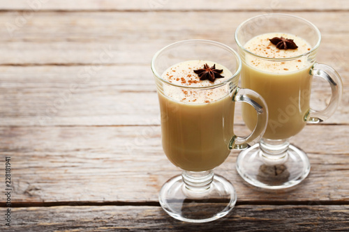 Eggnog in glasses with star anise on wooden table