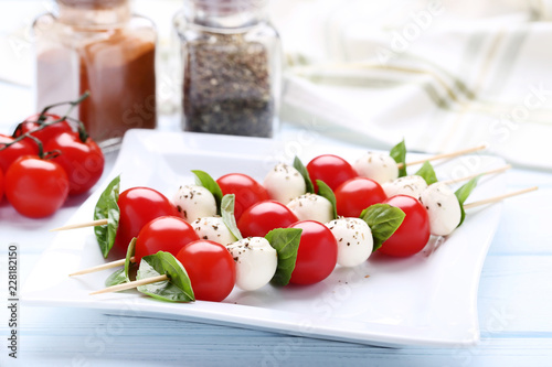 Sticks with mozzarella, tomatoes and basil leafs on wooden table