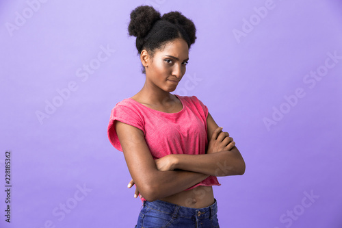 Photo of offended or naughty african american woman standing with arms folded, isolated over violet background
