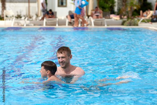 Cute caucasian boy is learning to swim in the swimming pool at the hotel. © Artem