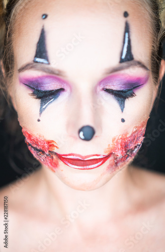 Closeup face of woman with creepy Halloween clown makeup looking into the camera. Creative  artistic  Halloween concept