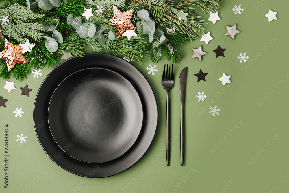 Christmas table setting. Black tableware and decoration with fir-tree branch. Flat lay, top view. Christmas table setting. Black tableware and decoration with fir-tree branch. Flat lay, top view.